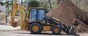 Backhoe in front of mulch piles