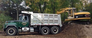 excavator on dirt mound loading truck